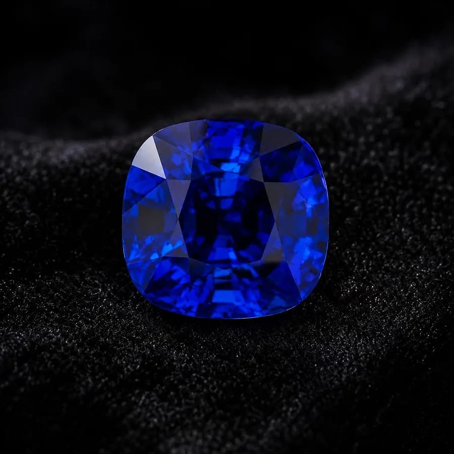 Deep royal-blue cushion-cut sapphire face-up on dark cloth