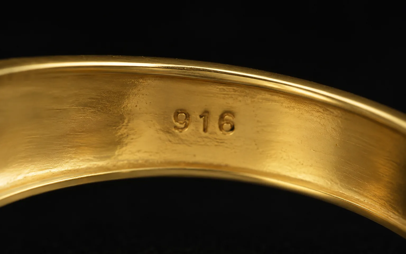 The inside of a gold bangle stamped 916